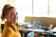 © Wavebreak Media - Young adult woman smiling at camera in bright office workspace, wearing yellow sweater