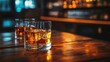 © thenort - Two glasses of amber liquor with ice on a rustic wooden bar top.