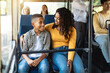 © Prostock-studio - Happy Family On The Bus. Portrait of smiling young African American woman and boy sitting and going on a public transport, lady hugging son and looking at each other, enjoying ride or travel