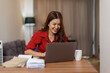 © David - Happy asian woman using laptop while working remotely from home in living room