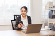 © David - Happy asian woman works at home and uses a smart phone and a notebook laptop computer in the home office. Woman working on desk with using calculator, financial planning finance accounting.