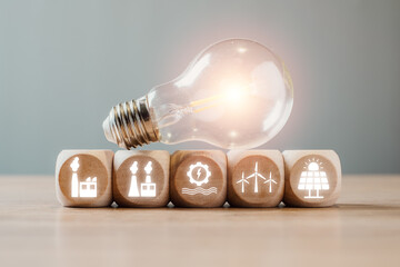 light bulb with renewable energy icons on wooden blocks, symbolizing smart grid technology and susta