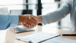 © tong2530 - Advisor and client handshake after financial consultation, mutual agreement atmosphere, bright modern office, documents and laptop visible