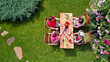 © Iuliia Sokolovska - Family and friends eating together outdoors on summer garden party in park. Aerial view of table with food and drinks on grass from above. Leisure, holidays and picnic concept