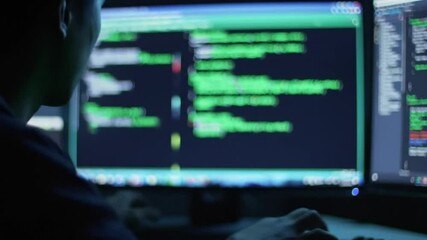 Hacker, coding and computer screen for cyber attack, security virus or malicious software at night. Mysterious unknown user black hat hacking on desktop PC or AI app for theft or fraud in dark room