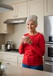 © Nurbaity - Senior woman drinking coffee in kitchen smiling