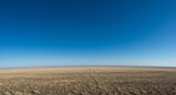 Photo of a Brown Plowed Field Under Blue Sky