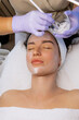 © MarijaBazarova - Close-up of a professional esthetician applying facial treatment with a brush to the face of a young woman during a skincare procedure in a beauty salon
