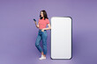 © ViDi Studio - Full body side profile view young woman she wear red striped t-shirt casual clothes big huge blank screen mobile cell phone with area using smartphone isolated on plain pastel light purple background.