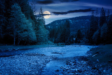 Wall Mural - mountain landscape with river at night. mysterious scenery with stones in the water and forest on th