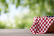 © Nittaya - Red checkered picnic blanket on wooden table outdoors