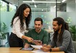 © Vooglo.com - Three colleagues are collaborating on a project using a tablet and reviewing documents in the office
