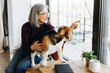 © Maria Vitkovska - Smiling senior woman showing something through window to her beagle dog