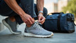 © Arra Vais - Man Tying Sneakers while Preparing for Travel with Blue Duffel Bag in Urban Setting for Travel Blogs, Lifestyle Websites, Adventure Guides, and Fitness Articles