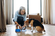 © Maria Vitkovska - Mature woman pouring dog food into bowl for beagle dog at home