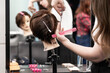 © Iryna - Close-up of student hands using scissors to cut synthetic hair on mannequin in beauty training session