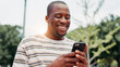 © peopleimages.com - Park, black man and hands with smartphone for social media, online communication and comment for reel. Outdoor, male person and laughing with mobile for application, funny joke and chat with contact