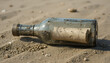 © AgustinusAdi - An old, dirty glass bottle with a wooden cork, containing a secret rolled-up paper, lying on the sandy shore of a beach