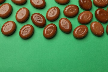 Wall Mural - many tasty caramel candies on green background, flat lay. space for text