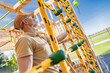 © Tomasz Zajda - Worker Inspects Climbing Structure at Playground Construction Site in Bright Daytime
