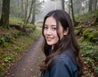 © Worldwide - Young woman smiling in forest path with greenery and mist in serene outdoor setting, portrait photography