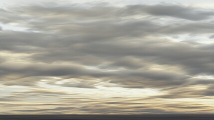 A dramatic sky with dark and light clouds, transitioning from a deep blue to a warm golden hue.