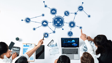 Fototapete - A top-down view of a corporate meeting showcasing teamwork, digital connections, and data analysis on laptops, papers, and charts in a modern office space. Amity