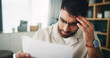 © Azee Jacobs/peopleimages.com - Remote work, man and stress in home with paper, reading and finance crisis in startup. Entrepreneur, mental health and headache in living room with invoice error, document and upset for business debt