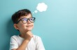 © Vadym - Cute boy wears glasses with thought bubble above head against pastel blue background. Smiling child idea looking up. Face expression, emotions of thinking, imagination, childhood. Education, school