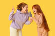 © Pixel-Shot - Young ginger woman and her cute daughter with microphone singing on yellow background