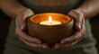 © mdshafiq - Hands holding candle representing hope and warmth, with soft glowing light