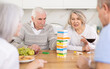 © JackF - Elderly happy people playing Jenga at home, woman is removing a wooden block from the tower and the others are watching