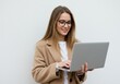 © Vooglo.com - Young woman in coat and eyeglasses holding laptop and smiling against a white background
