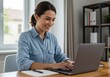 © Vooglo.com - Smiling woman working on a laptop at her desk in a bright home office environment
