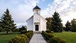 © Khozinul - Serene exterior view of a charming white church with a steeple, surrounded by lush green grass, evergreen trees, and manicured bushes on a sunny day.