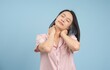 © Timeimage - Young woman practicing neck stretches for relaxation against a light blue background during her self-care routine