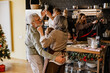 © Drobot Dean - An elderly white man and woman dance together in a decorated kitchen with a Christmas tree. The family members, including women and children, prepare food and celebrate the holiday indoors.