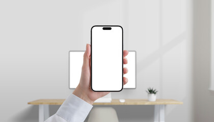 Leinwandbilder - Smartphone with blank white screen held in hand in modern office, desktop computer in background, perfect for mobile UI mockup