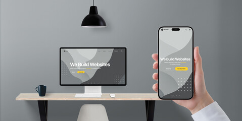 Fototapete - Digital transformation concept with responsive business website shown on phone and desktop display, hand holding device in modern office