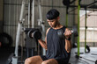 © wichayada - Muscle Development. Man performing seated dumbbell press in gym for strength training.