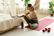 © Maria Vitkovska - Young woman choosing online training program on laptop in bedroom