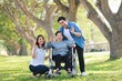 © Mallika - Senior Asian Woman in Wheelchair with Family Outdoors ,Caregiving and Support