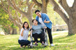 © Mallika - Senior Asian Woman in Wheelchair with Family Outdoors ,Caregiving and Support
