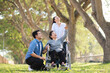 © Mallika - Senior Asian Woman in Wheelchair with Family Outdoors ,Caregiving and Support