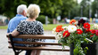 © Thanakit  - Elderly couple sitting on bench in park, surrounded by vibrant flowers, enjoying peaceful moment together