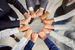 © Studio Romantic - Top-down shot of business people standing in a circle and holding fists together, working together in the office. Emphasizing teamwork, collaboration, and unity within the work team.