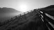 © TJantunen - Wooden Fence on Grassy Hillside with Mountains in Monochrome