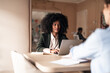 © Jelena - Professional Woman Using Laptop During Business Meeting in Modern Office Setting