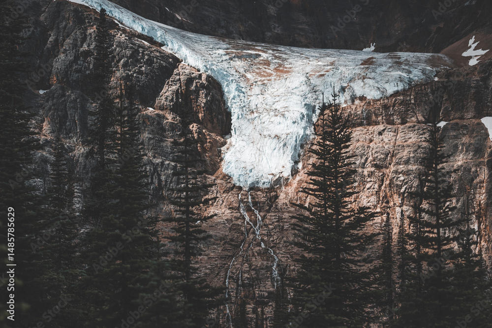 moody glacier view among the rocks with falling water in the middle fo ...