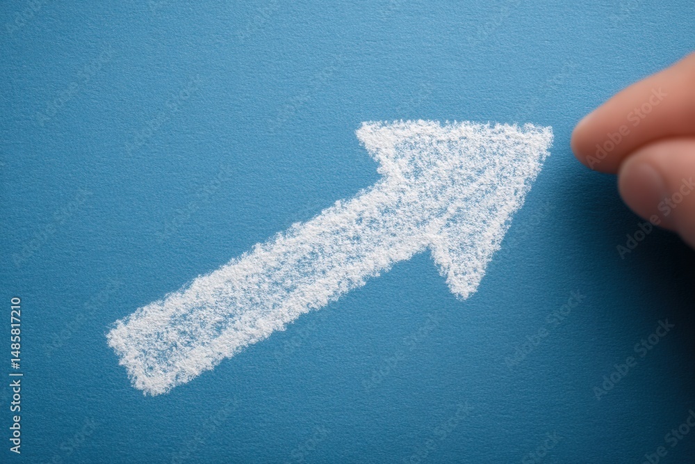 A hand is about to complete the drawing of a white arrow pointing upwards on a vibrant blue surface. The arrow symbolizes growth, progress, and direction, conveying a positive message.